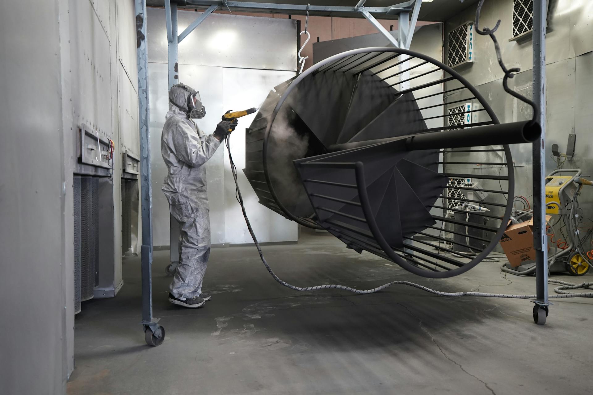 Pièce métallique en cours de thermolaquage par projection électrostatique